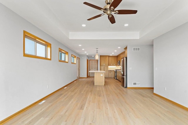 unfurnished living room featuring light wood finished floors, a raised ceiling, and visible vents