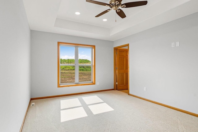 unfurnished room featuring recessed lighting, a raised ceiling, light colored carpet, and baseboards