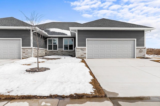 view of front of house featuring a garage, concrete driveway, a shingled roof, and stone siding