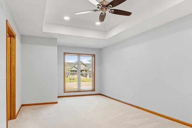 unfurnished room with recessed lighting, light colored carpet, a ceiling fan, baseboards, and a tray ceiling