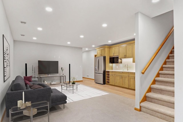 living room featuring recessed lighting, light carpet, baseboards, stairway, and light wood finished floors