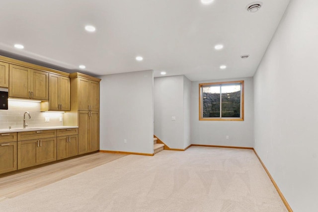 kitchen with tasteful backsplash, visible vents, baseboards, light countertops, and a sink