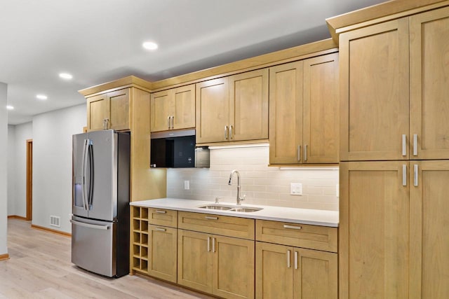 kitchen featuring light countertops, backsplash, a sink, and stainless steel fridge with ice dispenser