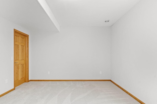 spare room featuring light colored carpet and baseboards