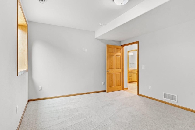 empty room featuring visible vents, light carpet, and baseboards