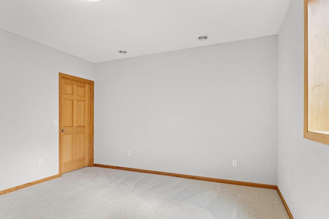 spare room featuring baseboards and light colored carpet