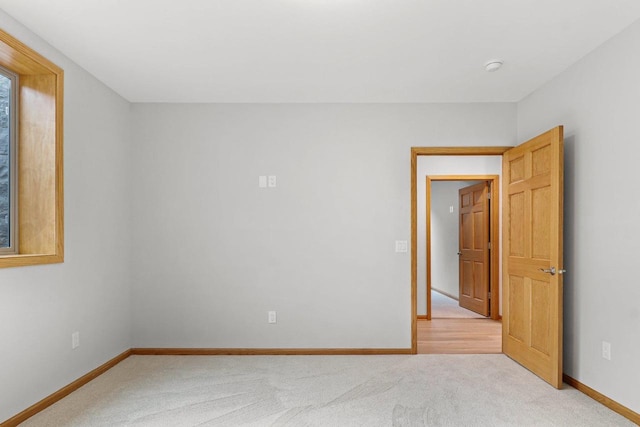 unfurnished room featuring baseboards and light colored carpet