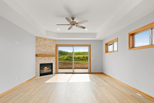 unfurnished living room with light wood-style floors, plenty of natural light, and a raised ceiling