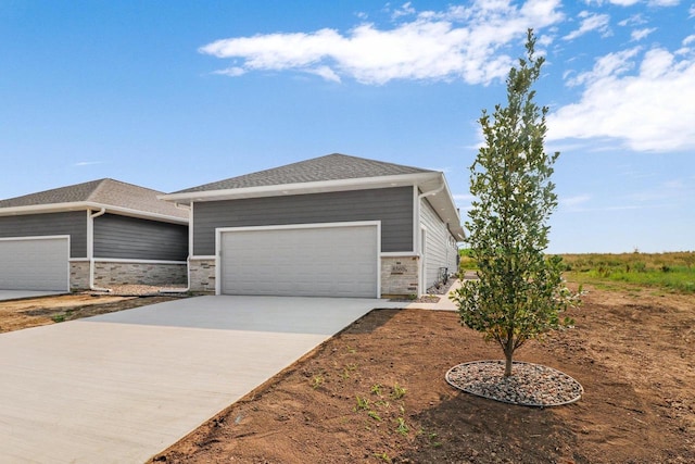 view of front of home featuring an attached garage, stone siding, and driveway