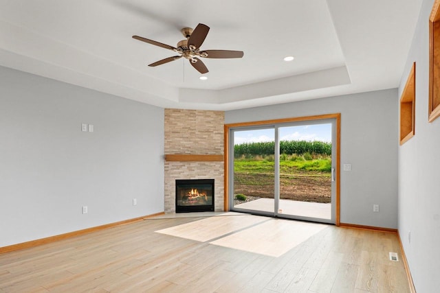 unfurnished living room with a raised ceiling, baseboards, and light wood finished floors