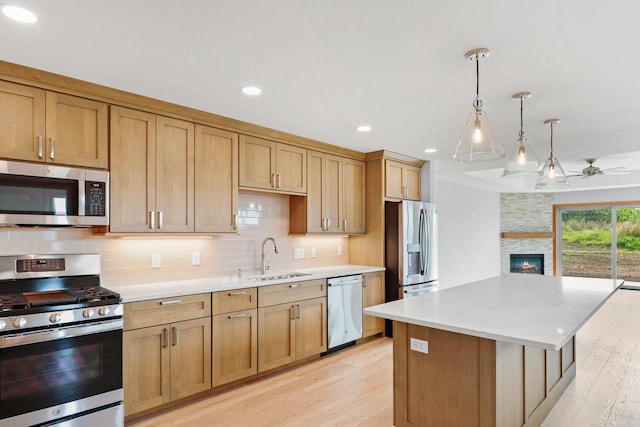 kitchen with stainless steel appliances, tasteful backsplash, a sink, and light wood-style floors