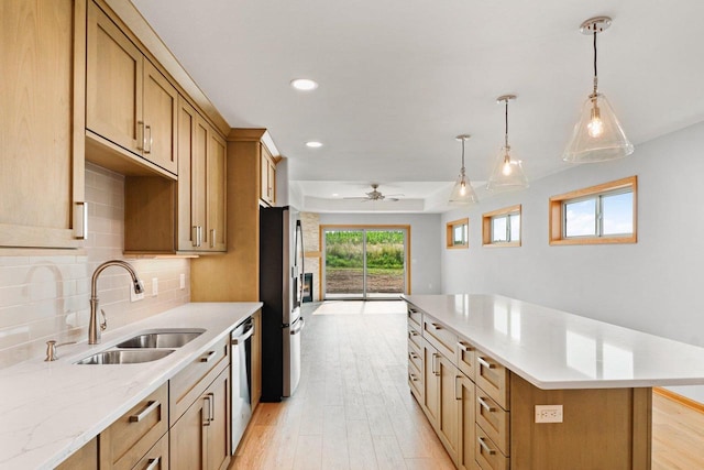 kitchen with stainless steel appliances, a kitchen island, a sink, light wood-type flooring, and decorative backsplash