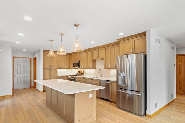 kitchen with visible vents, light wood-style flooring, appliances with stainless steel finishes, a center island, and backsplash