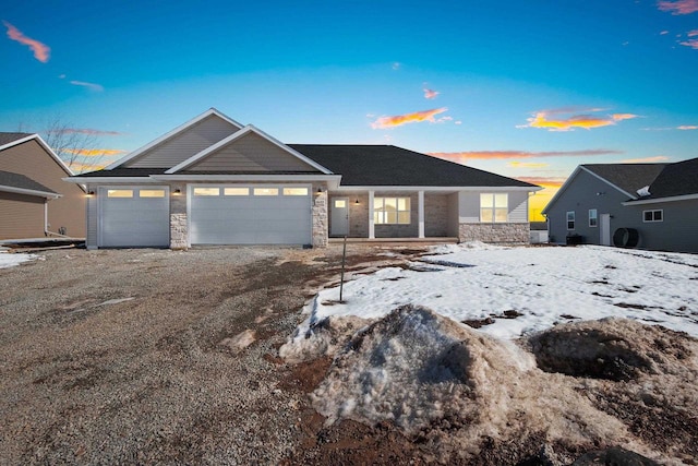 view of front of house with driveway, stone siding, and a garage