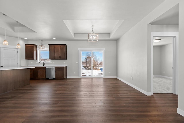 kitchen featuring a raised ceiling, light countertops, hanging light fixtures, and stainless steel dishwasher