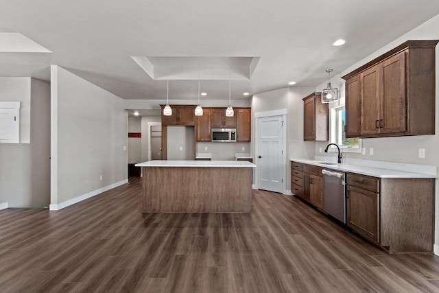 kitchen with a center island, hanging light fixtures, a tray ceiling, stainless steel appliances, and light countertops