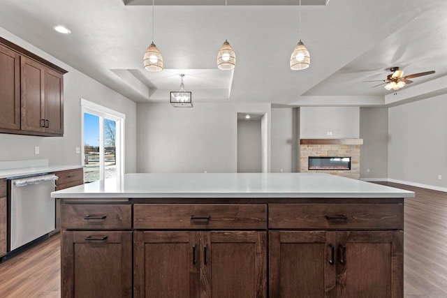 kitchen featuring open floor plan, light countertops, stainless steel dishwasher, a tray ceiling, and pendant lighting