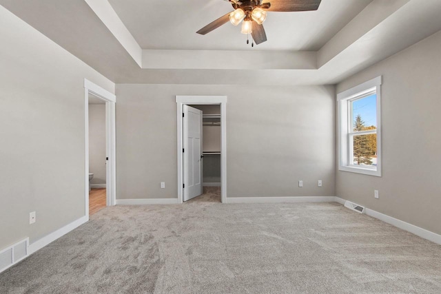 unfurnished bedroom with a raised ceiling, visible vents, and baseboards