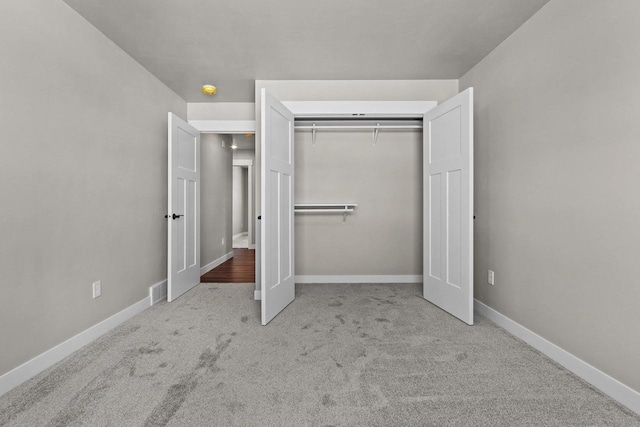 unfurnished bedroom with a closet, light colored carpet, and baseboards