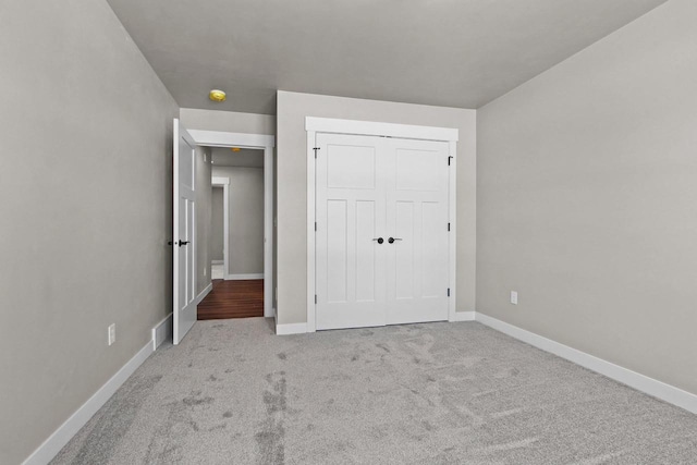 unfurnished bedroom featuring a closet, light carpet, and baseboards