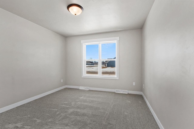 carpeted spare room with visible vents and baseboards