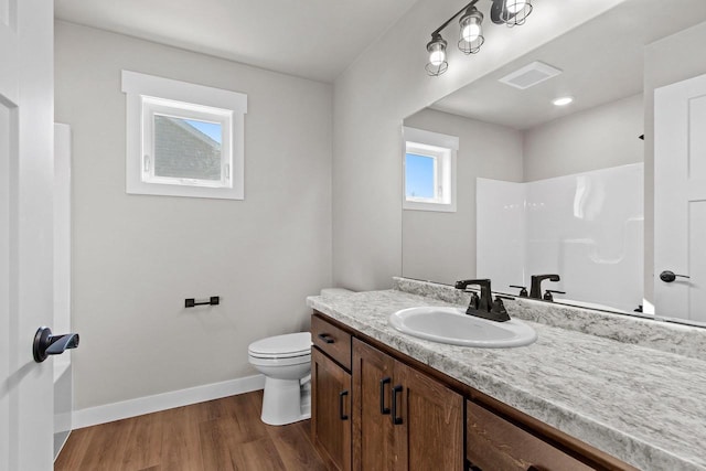 bathroom featuring visible vents, baseboards, toilet, wood finished floors, and vanity