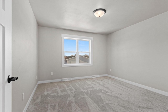 spare room with visible vents, baseboards, and light colored carpet