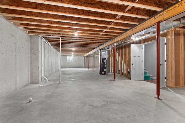 unfinished basement featuring heating unit and stairs