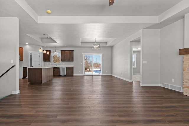 unfurnished living room with baseboards, visible vents, a raised ceiling, and dark wood-style flooring