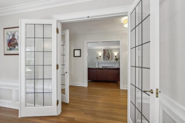 corridor with french doors, ornamental molding, and wood finished floors