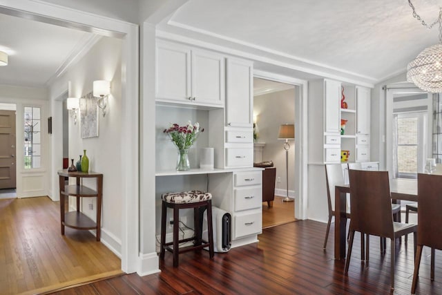 dining room featuring ornamental molding, dark wood finished floors, a notable chandelier, and plenty of natural light