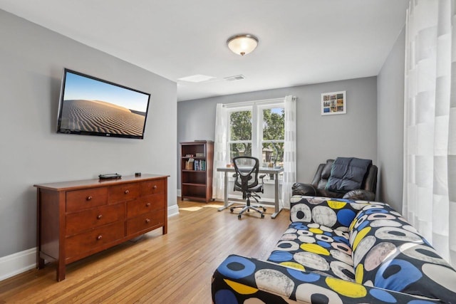 living area featuring light wood-type flooring, visible vents, and baseboards