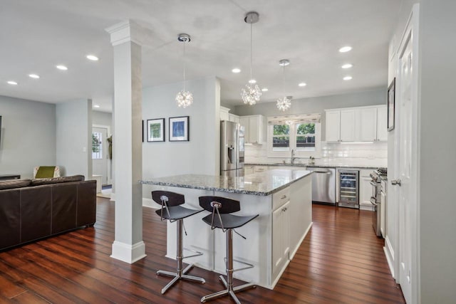 kitchen with wine cooler, stainless steel appliances, a kitchen island, white cabinetry, and open floor plan