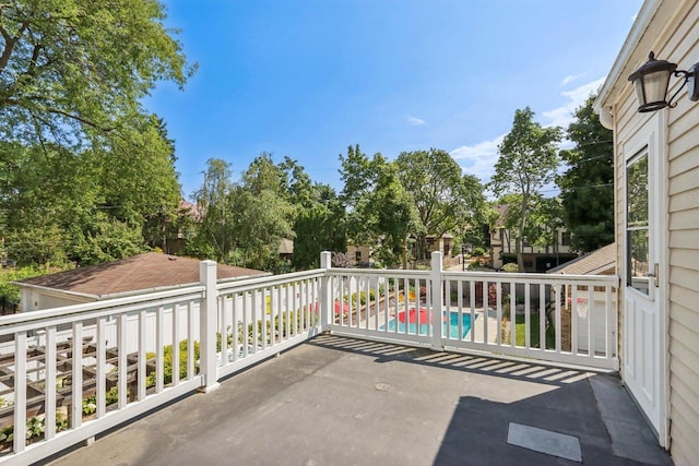 view of patio featuring an outdoor pool and a balcony