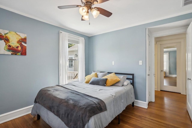 bedroom featuring crown molding, visible vents, a ceiling fan, wood finished floors, and baseboards