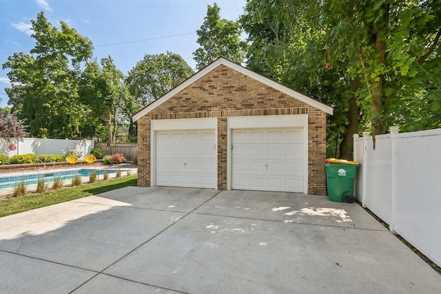 detached garage featuring fence and a fenced in pool