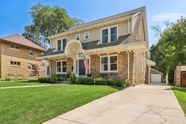 view of front of home with an outbuilding, brick siding, a shingled roof, a detached garage, and a front yard