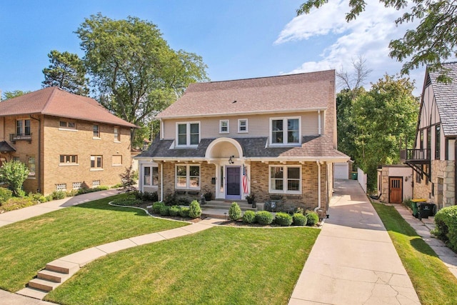 view of front of home with brick siding, a shingled roof, and a front yard