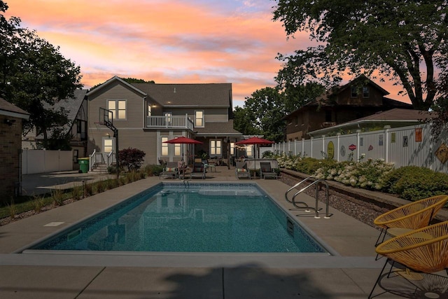 pool at dusk featuring fence, a fenced in pool, and a patio