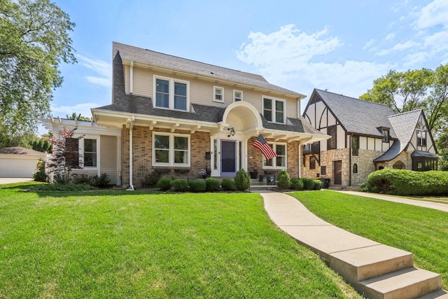 view of front facade featuring brick siding, a front yard, and a shingled roof