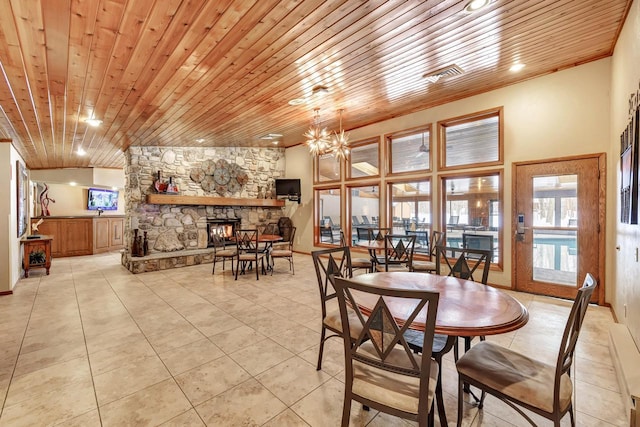 dining area featuring light tile patterned floors, a stone fireplace, wood ceiling, and a notable chandelier