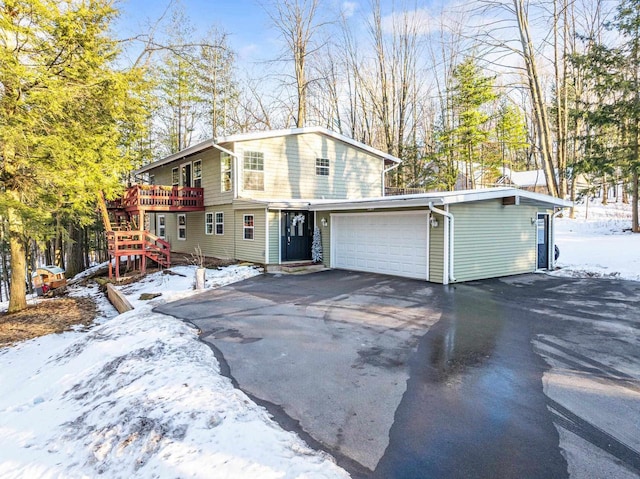 view of front of home with aphalt driveway, a deck, a garage, and stairs