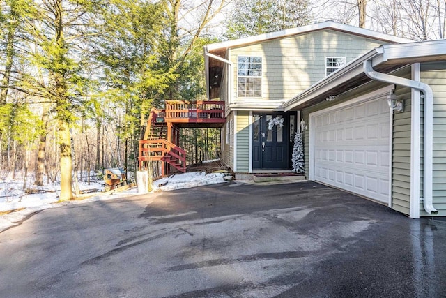 view of side of home featuring an attached garage, stairway, and aphalt driveway