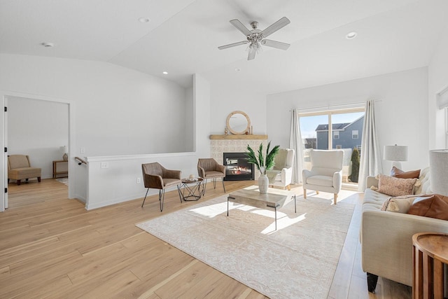 living area with light wood-type flooring, recessed lighting, a glass covered fireplace, and lofted ceiling