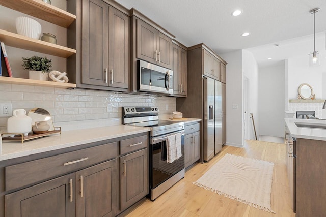 kitchen with decorative light fixtures, open shelves, stainless steel appliances, light countertops, and dark brown cabinetry