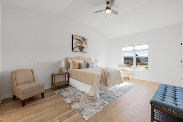 bedroom featuring light wood finished floors, baseboards, vaulted ceiling, and a ceiling fan