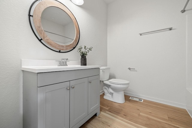 bathroom with visible vents, toilet, vanity, wood finished floors, and baseboards