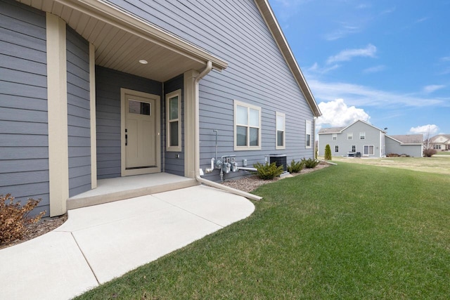 entrance to property featuring a lawn and cooling unit