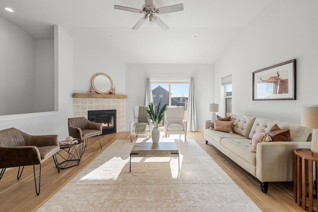 living room featuring light wood-style floors, a fireplace, vaulted ceiling, and recessed lighting