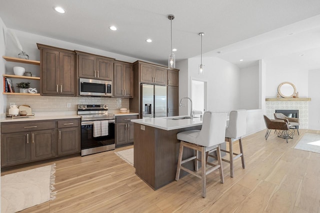 kitchen featuring a breakfast bar, stainless steel appliances, light countertops, a kitchen island with sink, and a sink